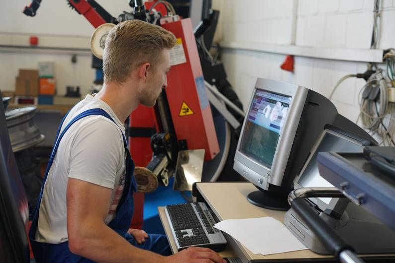 Foto, ein Werkstatt-Mitarbeiter sitzt an einem PC-Arbeitsplatz